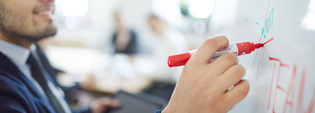 Market analyst making accent on teamwork in the following year while making report by whiteboard